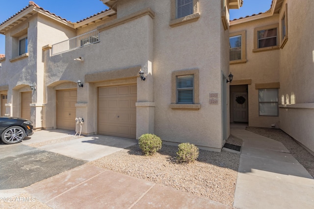 view of front facade featuring a garage, a tile roof, and stucco siding