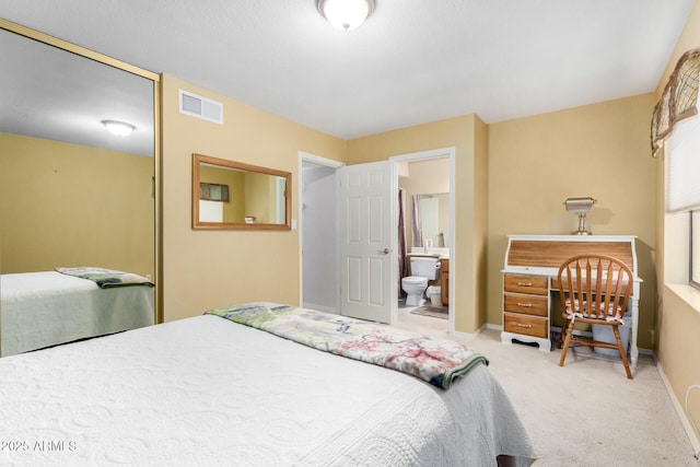 bedroom featuring ensuite bath and light carpet