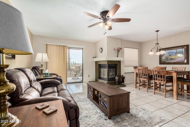 living room featuring ceiling fan with notable chandelier, a tile fireplace, and light tile patterned floors