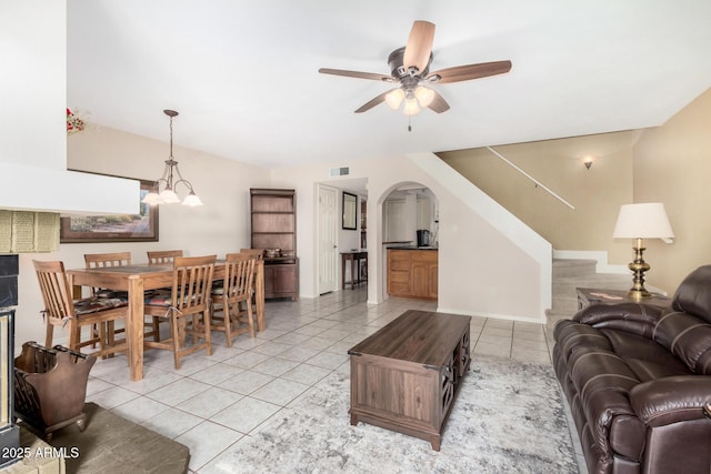 tiled living room featuring ceiling fan with notable chandelier