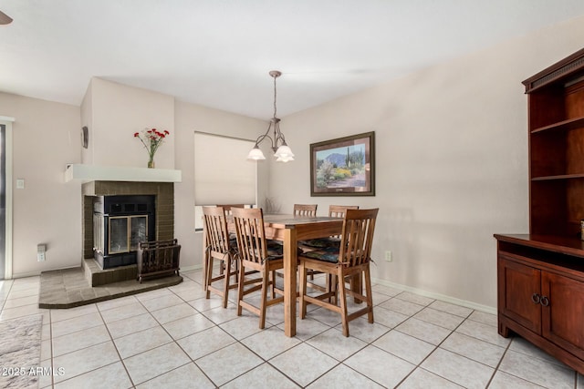 dining area with a brick fireplace, light tile patterned floors, and a notable chandelier