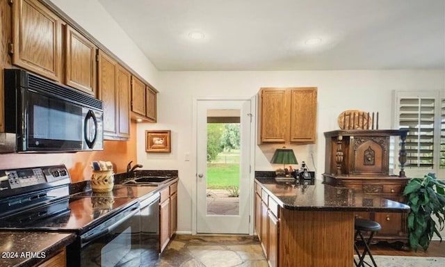 kitchen with black appliances, dark stone countertops, sink, kitchen peninsula, and a kitchen bar