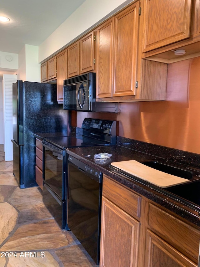 kitchen featuring dark stone counters and black appliances