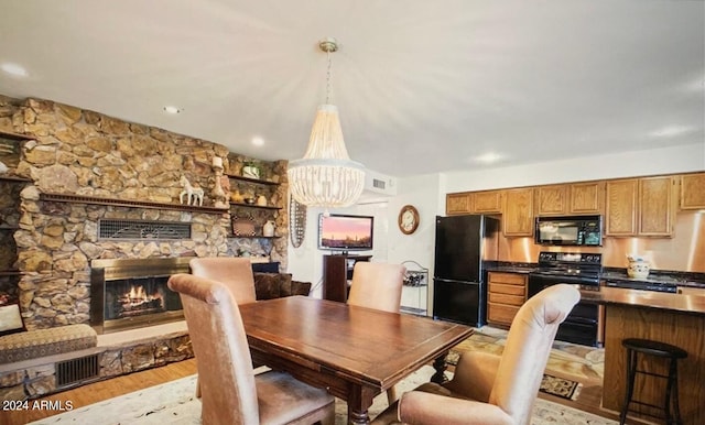 dining area with a fireplace, light hardwood / wood-style floors, and a chandelier