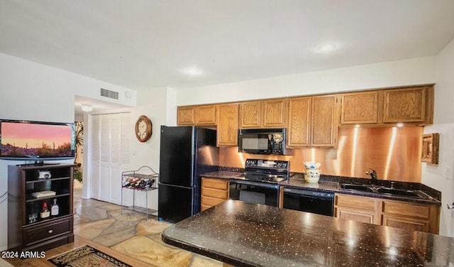 kitchen with dark stone counters, sink, and black appliances