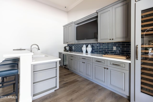 kitchen with beverage cooler, decorative backsplash, gray cabinetry, and a sink