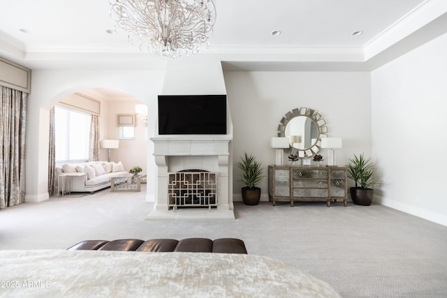 living area featuring a notable chandelier, ornamental molding, carpet floors, arched walkways, and a tile fireplace