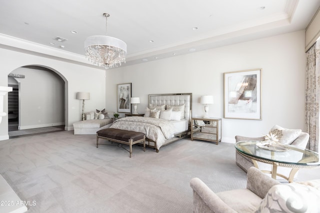 bedroom with an inviting chandelier, a raised ceiling, arched walkways, and light carpet