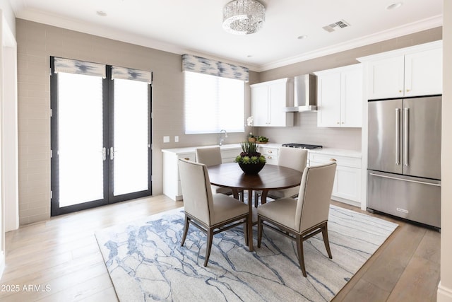 dining space with visible vents, french doors, light wood-style floors, and ornamental molding