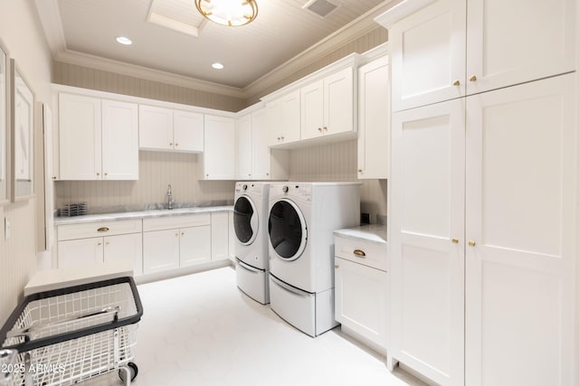 laundry room with visible vents, ornamental molding, a sink, washing machine and dryer, and cabinet space