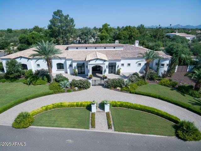 mediterranean / spanish-style home with stucco siding, a chimney, and a tile roof