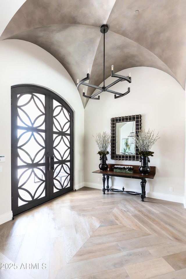 foyer with an inviting chandelier, baseboards, arched walkways, and lofted ceiling