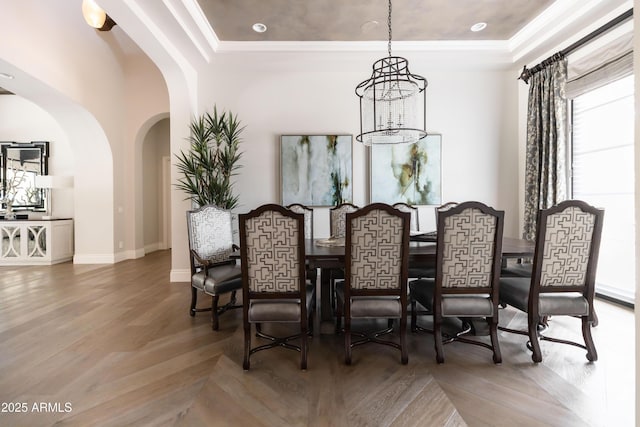 dining space featuring wood finished floors, baseboards, a tray ceiling, arched walkways, and a notable chandelier