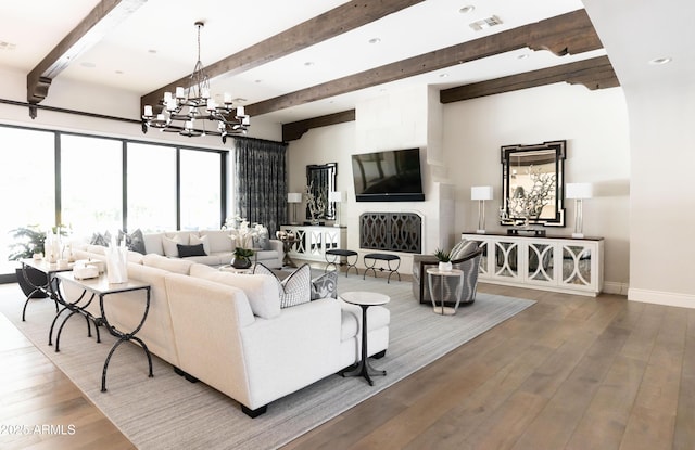 living room featuring visible vents, baseboards, beam ceiling, hardwood / wood-style flooring, and a notable chandelier