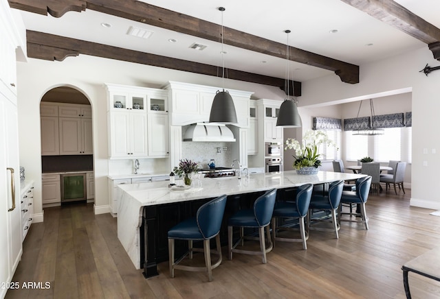 kitchen featuring a spacious island, backsplash, white cabinetry, and dark wood-style flooring