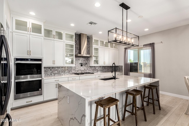 18139 W Oregon Ct, Litchfield Park, AZ 85340 - kitchen featuring wall chimney range hood, appliances with stainless steel finishes, a sink, backsplash, and light wood-style floors