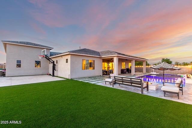 18139 W Oregon Ct, Litchfield Park, AZ 85340 - back of house at dusk featuring stucco siding, a patio, outdoor lounge area, and a ceiling fan