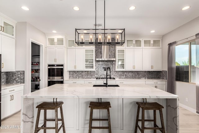 18139 W Oregon Ct, Litchfield Park, AZ 85340 - kitchen featuring double oven, recessed lighting, light wood-style floors, wall chimney range hood, and backsplash