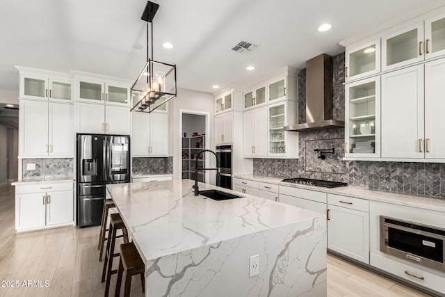 18139 W Oregon Ct, Litchfield Park, AZ 85340 - kitchen featuring stainless steel appliances, a sink, wall chimney range hood, tasteful backsplash, and an island with sink