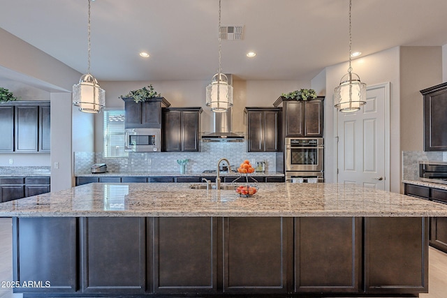 kitchen featuring appliances with stainless steel finishes, sink, hanging light fixtures, a large island, and dark brown cabinetry