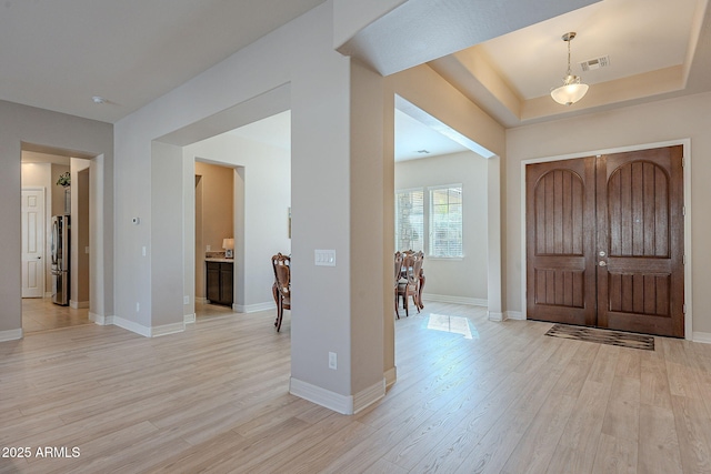 foyer featuring a tray ceiling and light hardwood / wood-style flooring