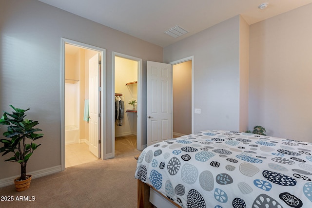 bedroom featuring light carpet, a spacious closet, and ensuite bathroom