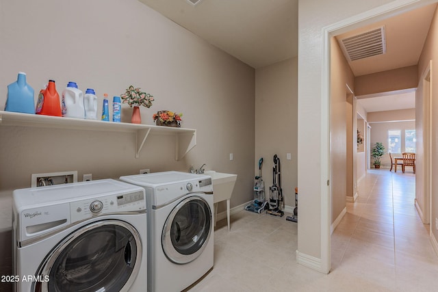 laundry area featuring separate washer and dryer, sink, and light tile patterned flooring