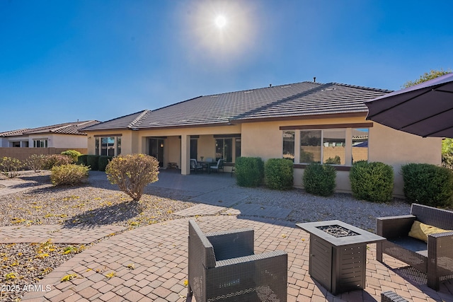 rear view of property featuring a fire pit and a patio area