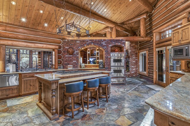 kitchen featuring appliances with stainless steel finishes, high vaulted ceiling, a kitchen island, and rustic walls