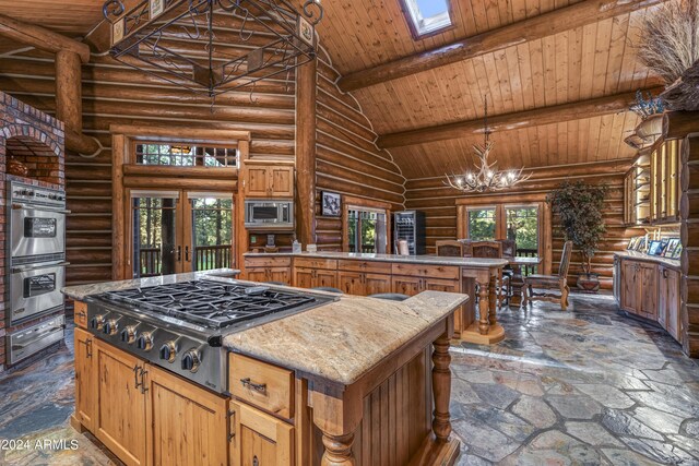 kitchen featuring a center island, stainless steel appliances, a notable chandelier, rustic walls, and high vaulted ceiling