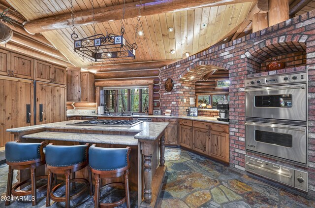 kitchen with beamed ceiling, wood ceiling, light stone counters, a center island, and appliances with stainless steel finishes