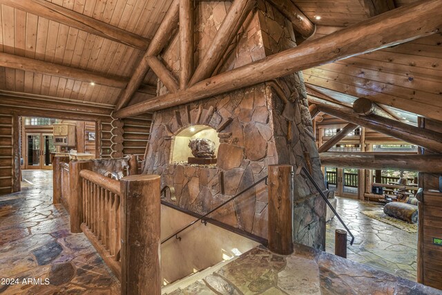 interior space with lofted ceiling with beams, wood ceiling, and rustic walls