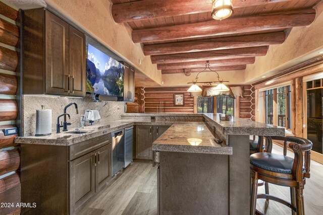 kitchen featuring a kitchen breakfast bar, beam ceiling, light hardwood / wood-style floors, kitchen peninsula, and sink