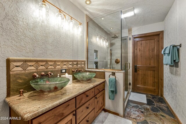 bathroom featuring vanity, a textured ceiling, and a shower with shower door