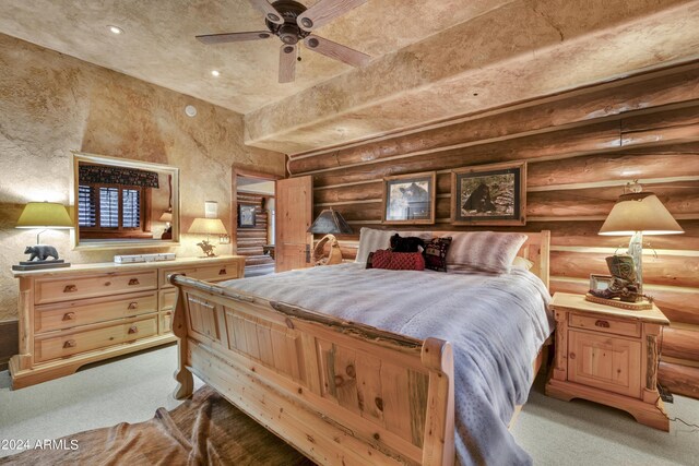 carpeted bedroom with rustic walls and ceiling fan