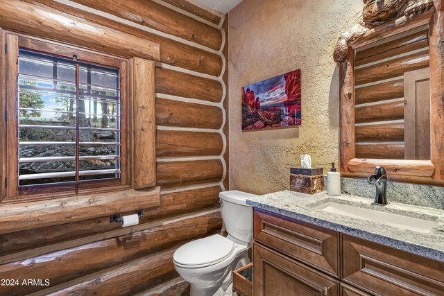 bathroom with rustic walls, toilet, and vanity