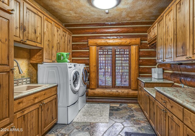 laundry room with rustic walls, cabinets, independent washer and dryer, and sink