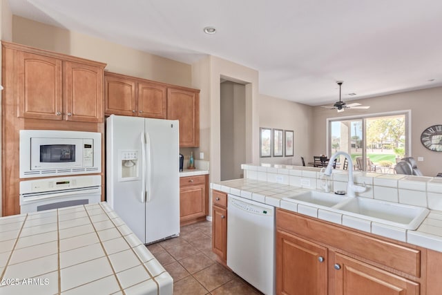 kitchen with light tile patterned flooring, white appliances, a sink, open floor plan, and tile counters