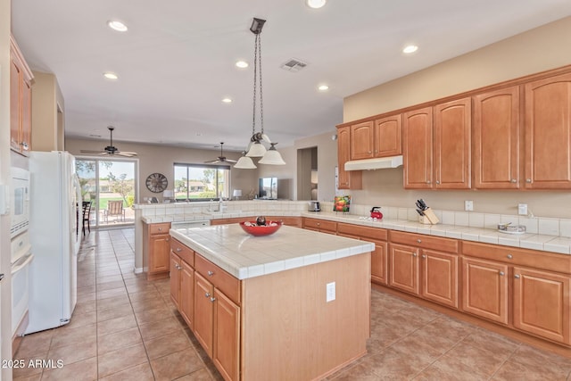 kitchen with recessed lighting, under cabinet range hood, a peninsula, white appliances, and visible vents