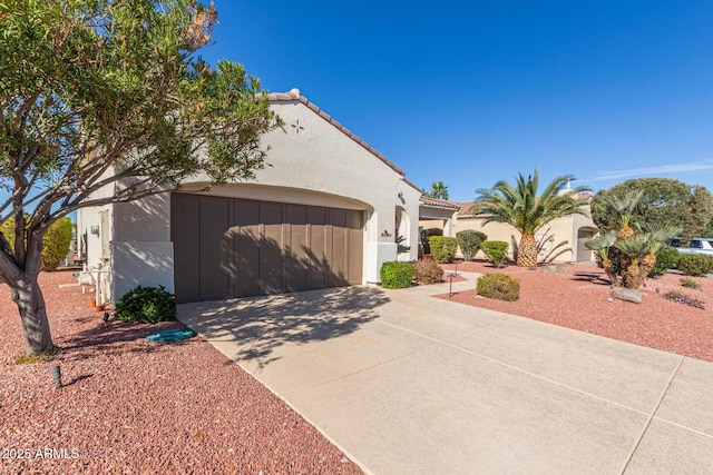 view of front of property featuring a garage, a tiled roof, concrete driveway, and stucco siding