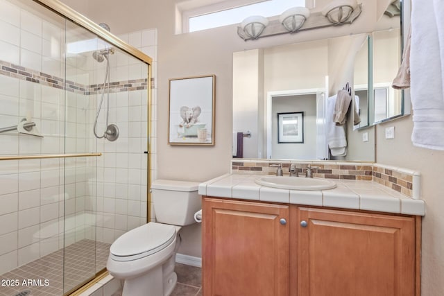 bathroom featuring toilet, a shower stall, and vanity