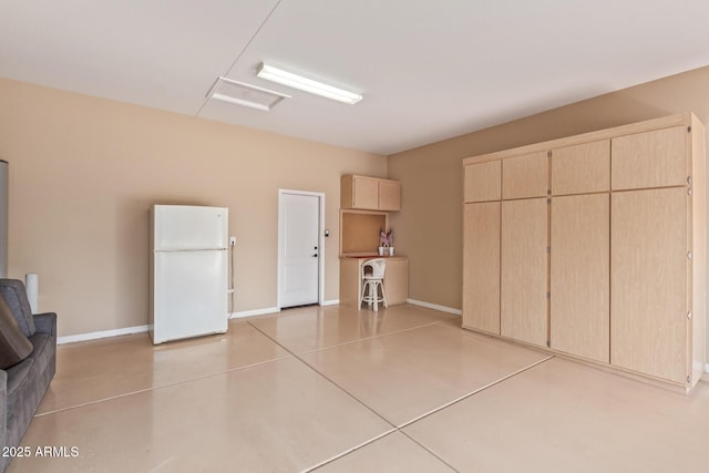 garage with baseboards and freestanding refrigerator