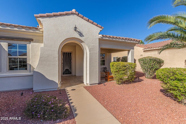 entrance to property with a tiled roof and stucco siding