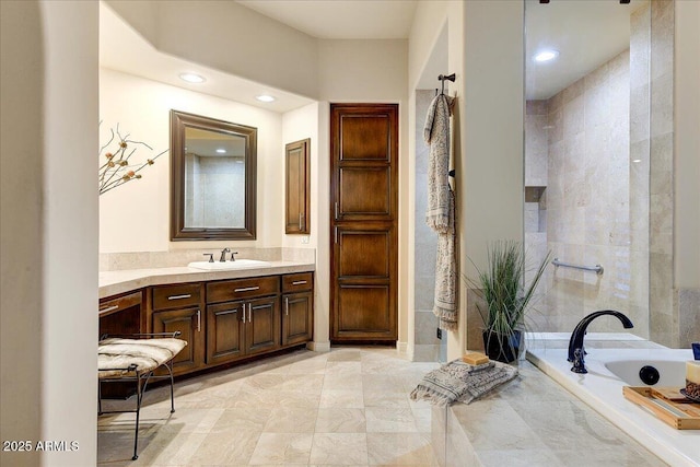 bathroom featuring tiled bath and vanity