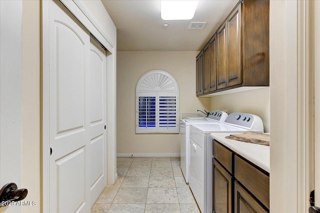 clothes washing area featuring cabinets and washing machine and clothes dryer