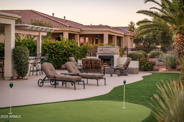 patio terrace at dusk featuring exterior fireplace