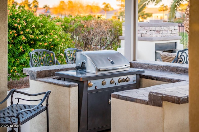 view of patio / terrace with a grill, a fireplace, and an outdoor kitchen