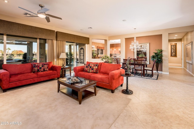 tiled living room featuring ceiling fan with notable chandelier