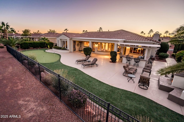 back house at dusk featuring a patio