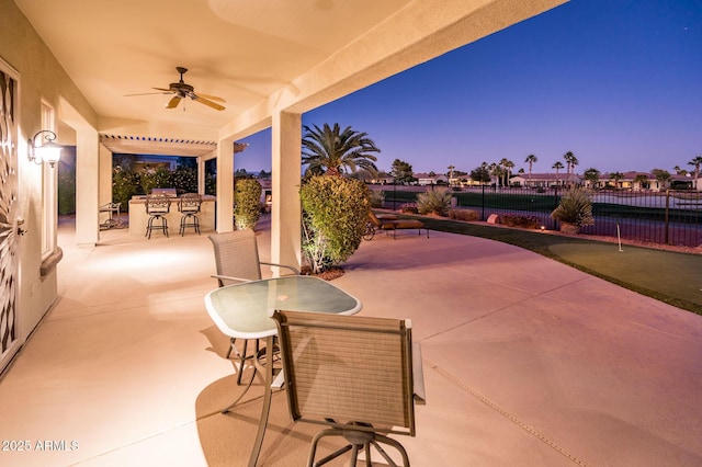 patio terrace at dusk with area for grilling and ceiling fan